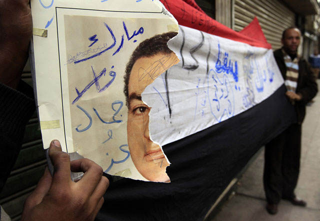 الصورة: متظاهر يحمل ملصقا ممزقا للرئيس المصري حسني مبارك خلال الاحتجاجات في القاهرة 29 يناير 2011