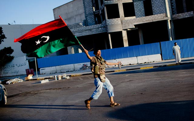 الصورة: مقاتل يردد شعارات مناهضة للقذافي وهو يحتفل في الشارع في طرابلس.