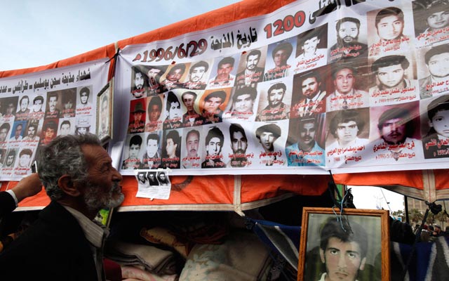 الصورة: محتج يلقي نظرة على صور المتظاهرين الذين قتلوا خلال انتفاضة ضد الزعيم الليبي معمر القذافي في مدينة بنغازي. رويترز