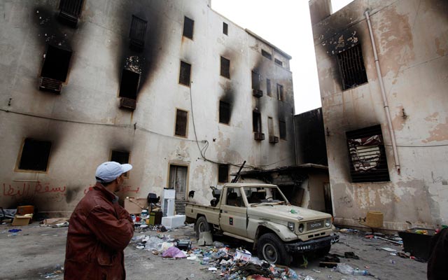 الصورة: متظاهر ينظر إلى مبنى الأمن الذي احرقه متظاهرين مناهضين للحكومة في بنغازي، رويترز.
