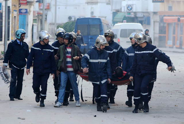 الصورة: رجال الانقاذ والشرطة يحملون شرطيا أصيب بجروح خلال اشتباكات مع متظاهرين