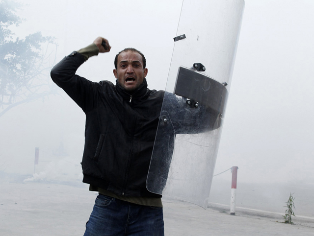 الصورة: متظاهر يهتف بشعارات مناهضة للنظام حاملا درعا حصل عليه خلال اشتباكات مع الشرطة