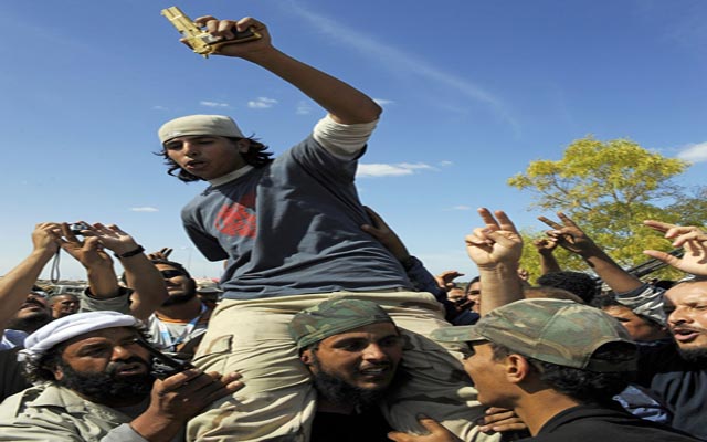 الصورة: ثوار يحملون مسدس القذافي الذهبي