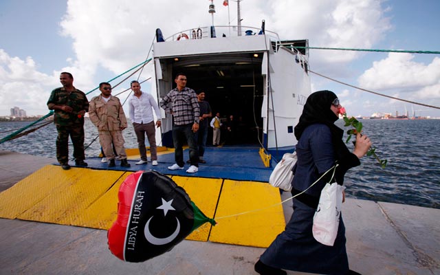 الصورة: سيدة تمر بالقرب من اول سفينة تحمل العمال منذ فبراير 2011 من قبرص إلى طرابلس. رويترز