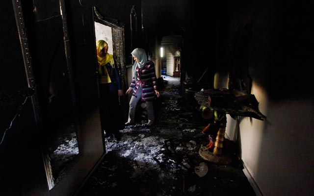 الصورة: سيدتان يتفقدان منزلهما الذي احترق خلال الإشتباكات في بني وليد. رويترز