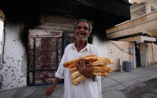 الصورة: فرحة اب بعد حصوله على الخبز من بعض المتبرعين في سرت. رويترز