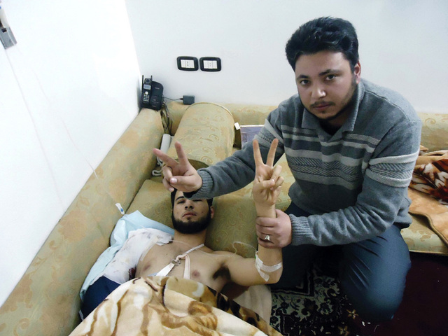 "الناشط خالد أبوصلاح (يمين) وأحد جرحى مذبحة بابا عمرو يرفعان إشارة النصر"