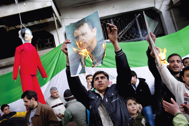 "سوريون يحرقون صوراً للأسد خلال تظاهرة في ضواحي إدلب"