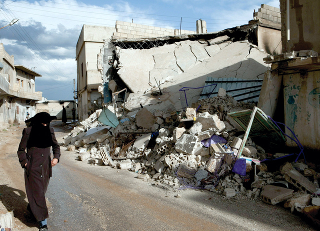 "سورية تسير قرب أبنية مهدمة بفعل قصف قوات النظام في قرية تفتناز بريف إدلب"