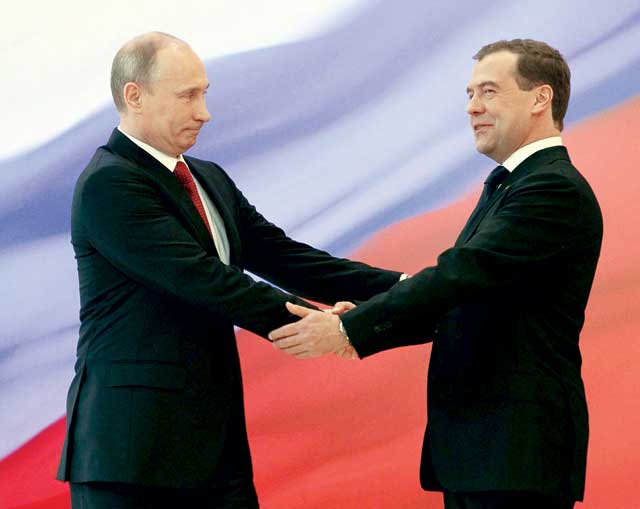 "بوتين يصافح مدفيديف لدى تسلمه منصبه الجديد (رويترز)"