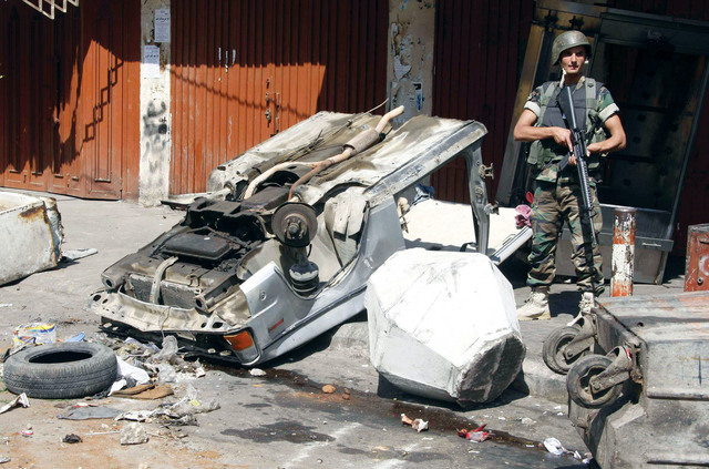 "جندي لبناني متحفزا بجوار سيارة معطوبة في شارع قريب من حي مسلم السني بطرابلس"