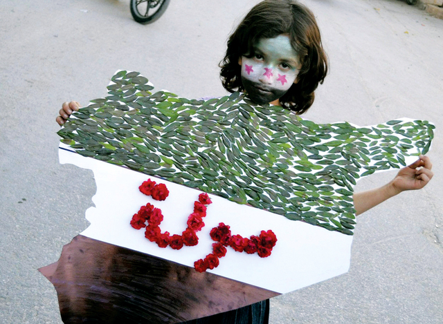 "طفلة سورية تحمل خارطة لسوريا مع لفظة حولة مكتوبة بالزهور الحمراء في بلدة نبل احتجاجاً على مجزرة الحولة"