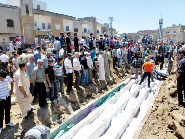 "سوريون يدفنون ضحايا مجزرة الحولة في قبر جماعي"