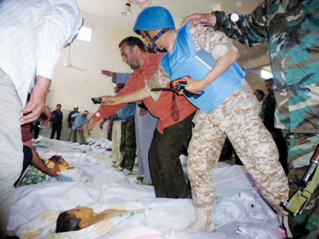 "أحد مراقبي الأمم المتحدة يعاين ضحايا المجزرة من الأطفال"