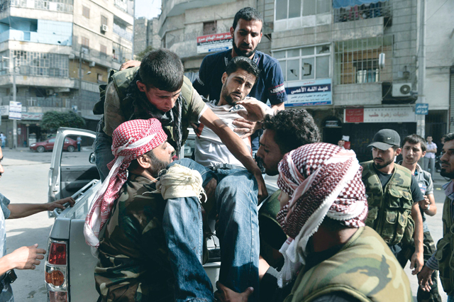 "مصاب يحمل على الأيدي في مسعى لمعالجته قبل أن تعالجهم قذائف القوات النظامية \tأ.ف.ب"