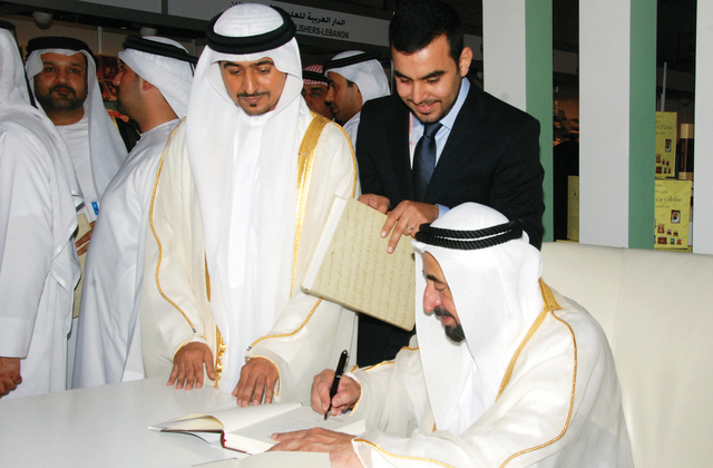 "حاكم الشارقة أثناء التوقيع على الكتب"