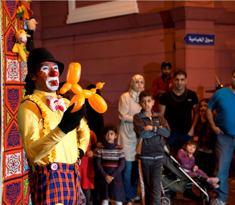 "وسط فرحة وانتظار الاطفال يقدم مهرج الجناح المصري اشكال الحيوانات المصنوعة من البالونات مجانا للاطفال متبادلا معهم اطراف الحديث الشقي وسط فرحة كبيرة من الهدية الملونة"
