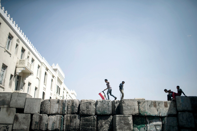 "شباب مصريون يسيرون على حواجز أسمنتية أقامتها قوات الأمن بالقرب من ميدان التحرير.\tإي.بي.ايه"