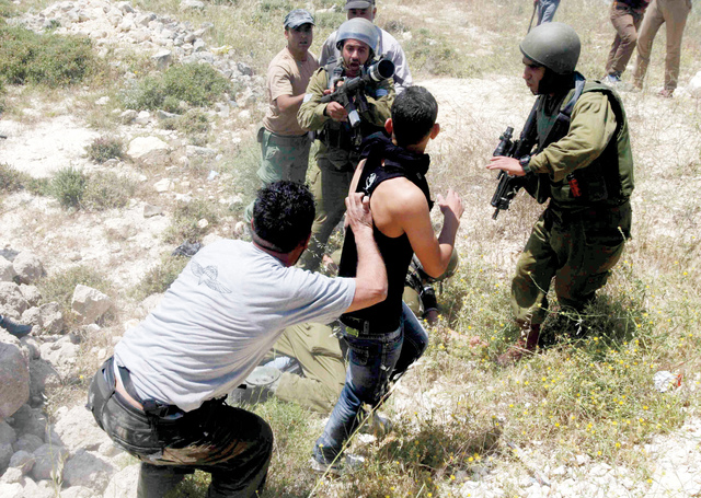 "شابان فلسطينيان من قرية عوريف (القريبة من مدينة نابلس) يواجهان جنود الاحتلال الذين يحرسون عصبة من المستوطنين الذين اقتحموا أراضي القرية رويترز"