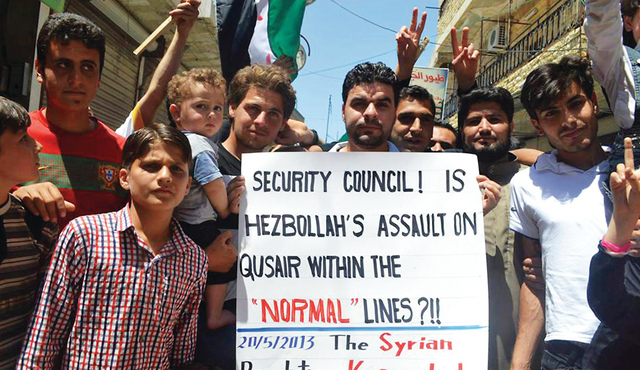 "متظاهرون في قرية كفرنبل التابعة لإدلب يحتجون على هجوم حزب الله اللبناني على مدينة القصير   \t أ."