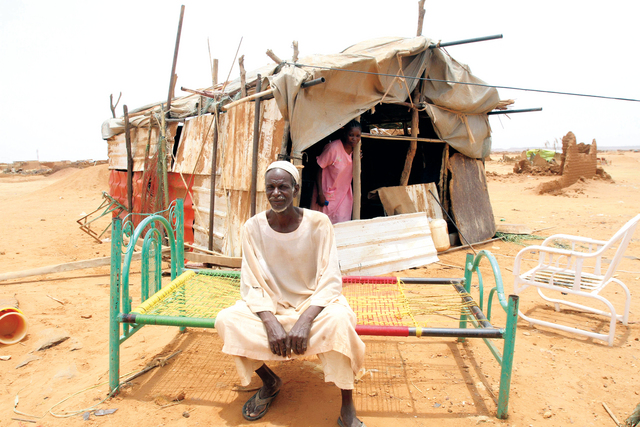 "سوداني يجلس أمام منزله المهدم بفعل الفيضانات التي خلفت عشرات القتلى     أ.ف.ب"