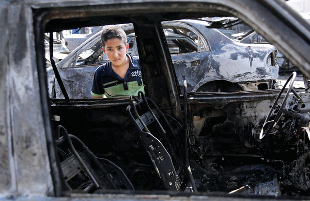 "طفل يُلقي نظرة على موقع تفجير في بغداد أمس \t\t\t «أ.ب»"