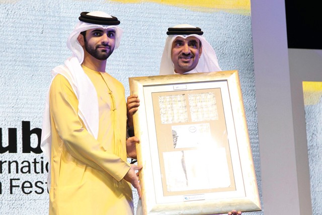 "منصور بن محمد يتسلم الطابع الخاص بالمهرجان من إبراهيم بن كرم"