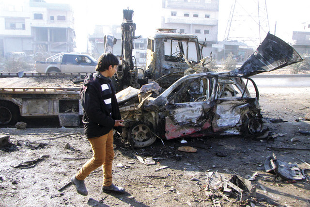"شاب سوري يمر بالقرب من سيارة وابنية مدمرة في حلب \tرويترز"