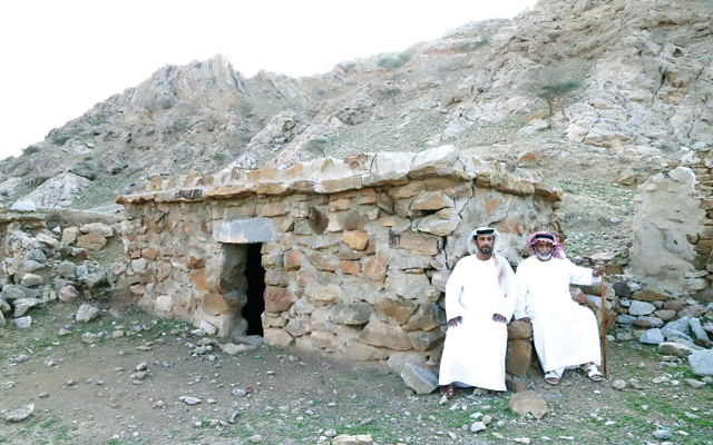"محمد حسن الشملي أمام بيته السابق المبني من الحجر وإلى جواره عبد الله الشحي تصوير - محمد حنيف"