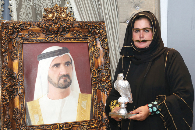 "زينب السيد \"أم سعيد\" تحمل درعاً تذكارية تكريماً لجهودها تصوير- موهان"
