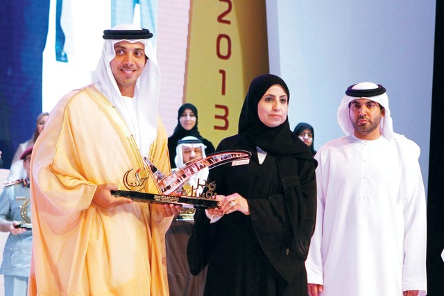 "منصور بن زايد يتسلم درع التكريم من أمل العفيفي"