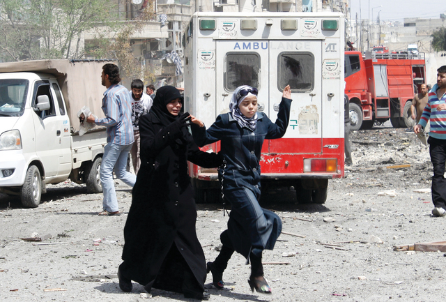 "امرأة وفتاة سوريّتان تبتعدان عن مبنى سكني تعرض لقصف من قوات النظام في حلب\tأ.ف.ب"