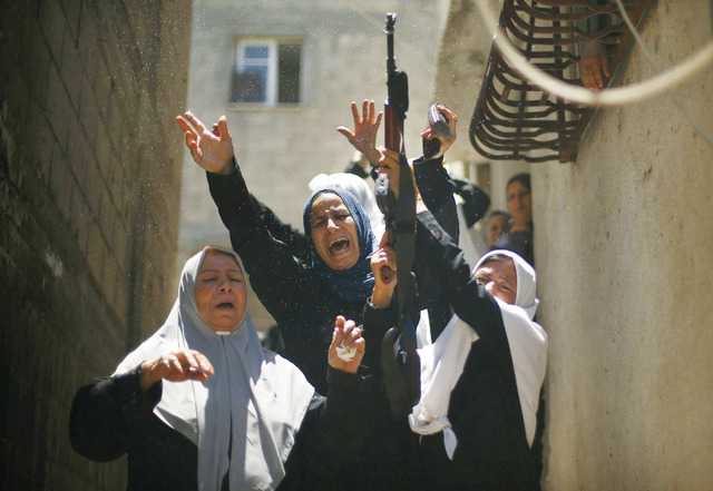 "فلسطينيات ينتحبن فيما تطلق إحداهن الرصاص في الهواء خلال تشييع شهيد من المقاومة.\tرويترز"