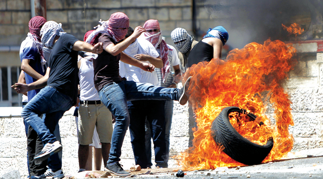 "فلسطينيون يشعلون إطاراً خلال مواجهات مع قوات الاحتلال في حي شعفاط بالقدس\tأ.ف.ب"