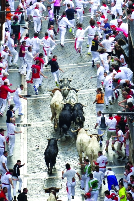 "Participants run in front of Torrestrella's bulls during the first bull-run of the San Fermin Festival, on July 7, 2014, in Pamplona, northern Spain. The festival is a symbol of Spanish culture that attracts thousands of tourists to watch the bull runs despite heavy condemnation from animal rights groups. AFP PHOTO / PEDRO ARMESTRE"