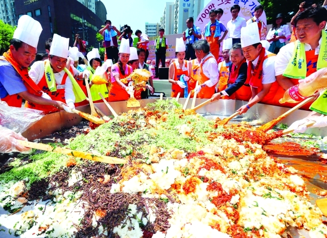 "epa04303323 Volunteers join to make bibimbap, a traditional Korean dish made with vegetables, sliced beef, steamed rice and hot pepper sauce, at an event in Seoul, South Korea, on 07 July 2014, to mark the 7th million beneficiary of the free meal service by a local charity organization, 'Bopfor.' The service began 26 years ago. EPA/STRINGER SOUTH KOREA OUT"
