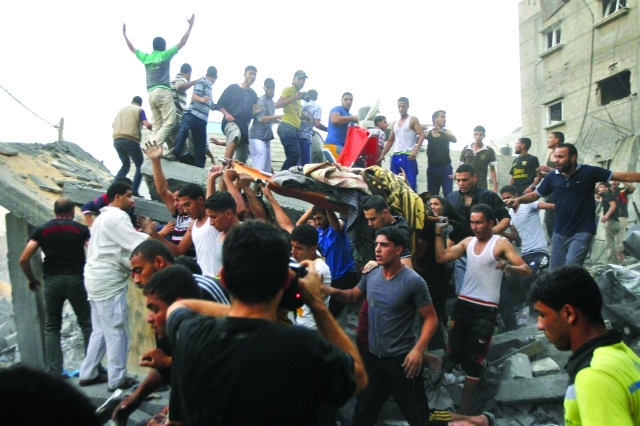 "فلسطينيون يحملون جثمان أحد الشهداء بعد تدمير منزل على رؤوس ساكنيه في رفح\tأ.ف.ب"