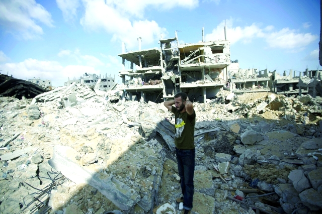 "فلسطيني يقف وسط الركام في حي الشجاعية الذي قصفته آلة الحرب الهمجية \t أ.ف.ب"