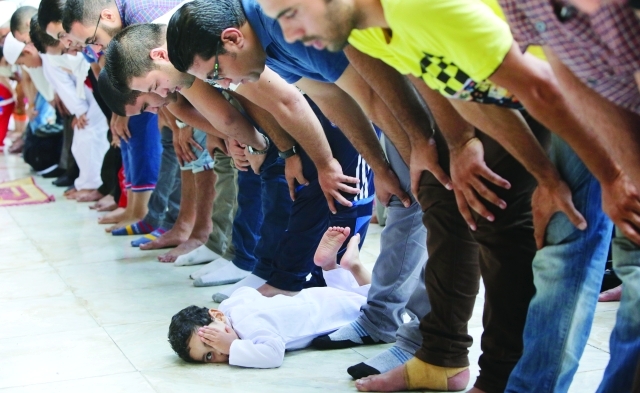 "طفل مصري مسترخٍ بين مصلين يؤدون صلاة العيد في جامع الأزهر \t أ.ب"