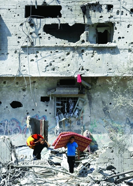 "فلسطينيان يحملان بقايا أثاث منزلهما بعد قصفه في حي الشجاعية     أ.ف.ب"