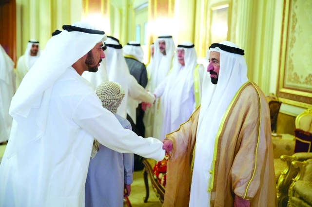 "سلطان القاسمي مصافحاً المهنئين بحضور أحمد بن سلطان القاسمي وسلطان بن محمد بن سلطان القاسمي"