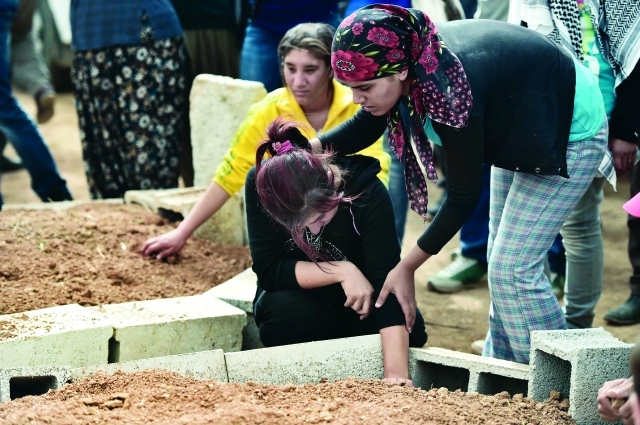 "عائلة كردية تبكي قريبها الذي قتل في معارك عين العرب بعد دفنه في مقبرة بتركيا أ.ف.ب"