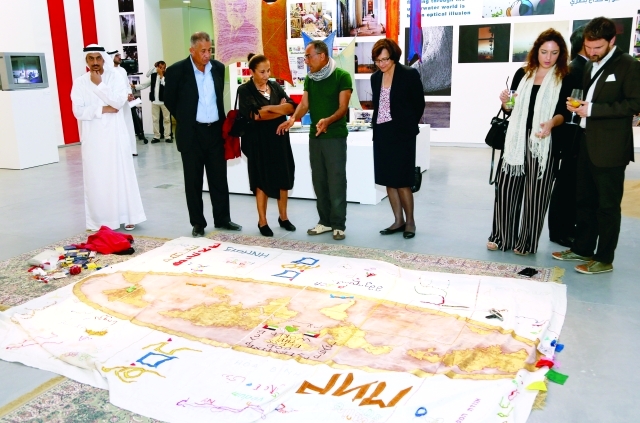 "الفنان الفاضل يتوسط هشام المظلوم ومجموعة من الحضور خلال حديثه عن عمله في المعرض\tتصوير ـــ محمود الخطيب"