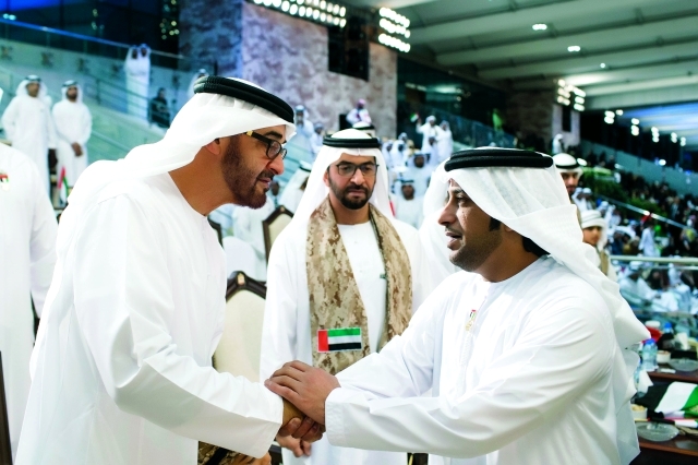 "ولي عهد أبوظبي مصافحاً بحضور حمدان بن زايد الفنان عيضة المنهالي"