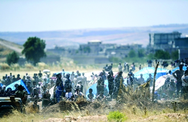 "نازحون على الجانب التركي من الحدود المقابل لعين العرب «أ.ف.ب»"