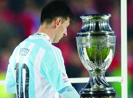 "Argentina's Lionel Messi walks with his silver medal past the Copa America trophy during the presentation ceremony after Chile defeated his team in the Copa America 2015 final soccer match at the National Stadium in Santiago, Chile, July 4, 2015. REUTERS/Ivan Alvarado (TPX IMAGES OF THE DAY)"