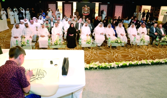"■ المر والعويس والسويدي والحضور يتابعون الخطاط الفتى عبدالله حسين حمدان خلال خطه البسملة في الافتتاح | البيان"