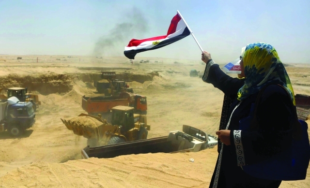 "مصرية ترفع العلم تحية للعاملين في المشروع عند انطلاقه ــ رويترز"