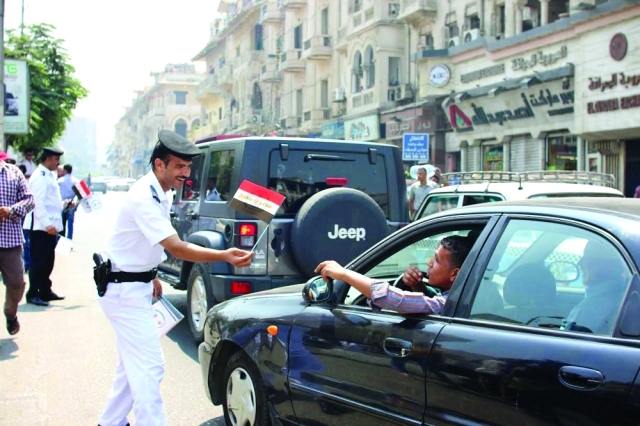 "■ شرطي يوزع الأعلام على المركبات"