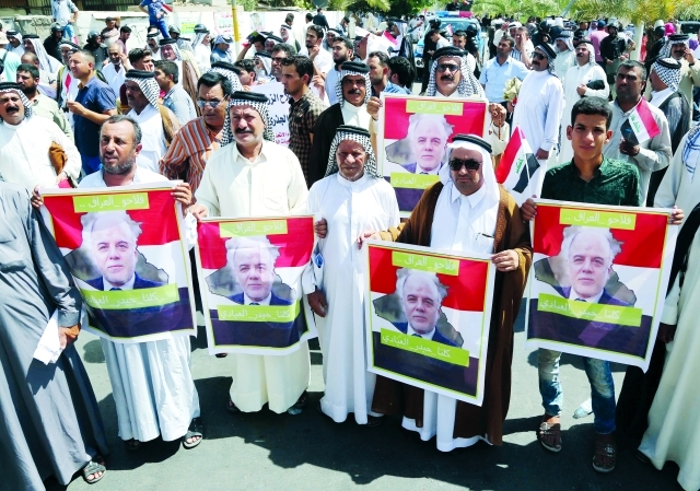 "■ عراقيون يحملون صور العبادي خلال تظاهرة تأييد في بغداد | أ.ب"